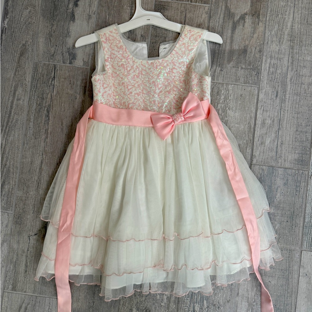 White, layers, dress with pink sparkles on top, trimmed in pink stitching.